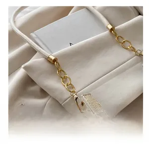 Macro detail of golden metal hardware and chain link on a beige woven shoulder bag