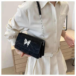 Close-up of black pleated leather handbag with silver butterfly clasp and chain strap