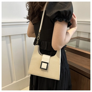 Detail of contrast stitching beige woven fabric bag with white leather flap and gold chain
