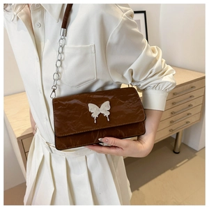 Brown pleated leather shoulder bag with silver butterfly clasp shown on shoulder