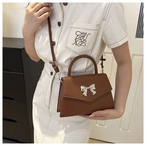 Caramel brown trapezoid handbag with silver metal bow and adjustable shoulder strap