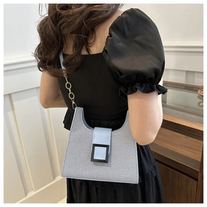Detail of blue textured fabric shoulder bag with large black buckle and chain strap