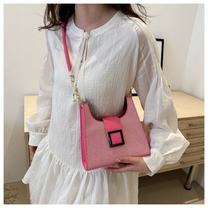 Detail of pink woven crossbody bag featuring a black square buckle and gold chain strap