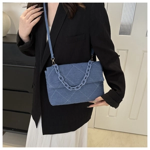 Detail of blue denim quilted shoulder bag with chic chunky chain and stitching