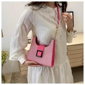 Detail of pink woven shoulder bag featuring a black square buckle and lace strap decor