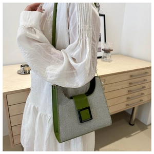 Detail of contrast stitching, green leather trim and black square buckle on the shoulder bag