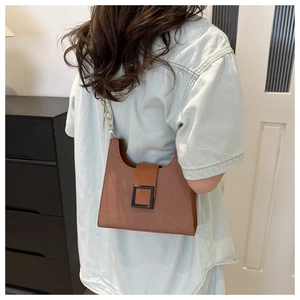 Detail of vintage brown shoulder bag with dark brown strap and large black square buckle