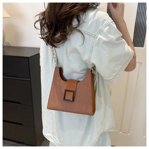 Close-up of caramel brown underarm bag with gold chain strap and vintage square buckle