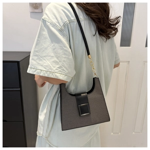 Detail of grey textured fabric and black leather shoulder bag with gold chain strap