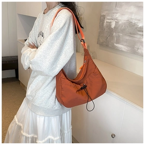 Detail of caramel nylon crescent bag featuring a drawstring design and adjustable strap