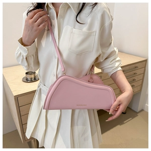 Detail of pink asymmetric geometric leather shoulder bag worn by model in a warm setting