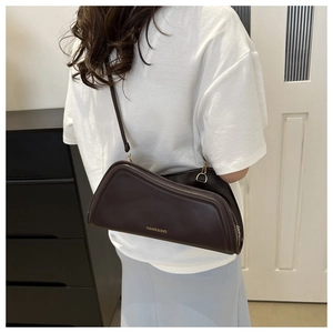 Vue détaillée d'un sac sous le bras en cuir marron avec lettrage doré sur modèle