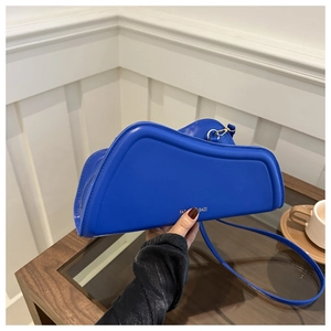 Detail of royal blue asymmetric handbag with gold hardware and fashion lettering