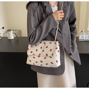 Detail of white corduroy tote bag with strawberry print and elegant chain strap