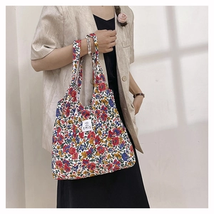 Detalle de bolso tote ligero de nailon con patrones florales coloridos y logo EMIS