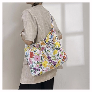 Close-up of a floral nylon tote bag featuring colorful patterns and a wide shoulder strap