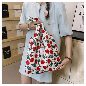 Detalle del bolso tote de nailon con flores rojas y etiqueta blanca de marca EMIS