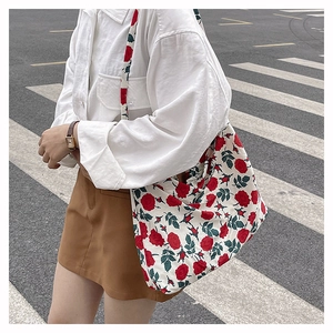 Detail of large nylon tote bag featuring red rose patterns on off-white fabric base