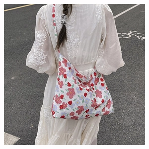 Floral print nylon crossbody bag detail on a model wearing a white bohemian lace dress