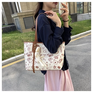 Close-up of white graffiti tote bag featuring cartoon prints and a plush rabbit pendant