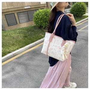 Outdoor street style view of a white graffiti tote bag with pink straps and plush bunny