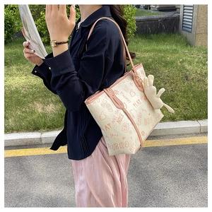 Detail of a beige tote bag with pink straps and a cute plush rabbit pendant charm