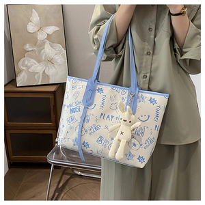 Detail of contrast tote bag with graffiti print and cute plush rabbit accessory