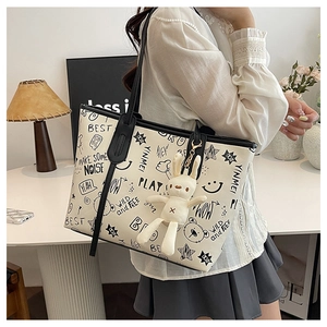 Detail of graffiti tote bag with rabbit plush charm and black shoulder straps on model