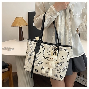 Detail of a white tote bag with black cartoon graffiti and a plush bunny keychain