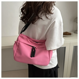 Detail van roze nylon crossbodytas met verstelbare riem en geweven ritskoordtrekker