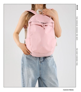 Detailed back view of pink lightweight nylon backpack worn by a model in a studio setting