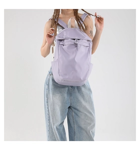 Close-up of lightweight lavender nylon backpack featuring BAG print and white top handle