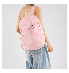 Rear view of a light pink nylon folding backpack with adjustable straps and side pockets