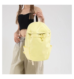 Detail of yellow lightweight nylon backpack featuring front zipper pocket and side pockets