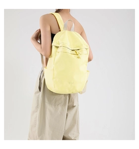 Light yellow canvas backpack on model with adjustable straps and multi-pocket design