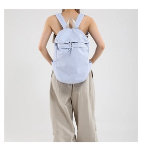 Rear view of a model wearing a lightweight light blue foldable drawstring backpack
