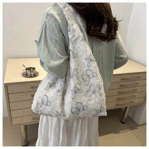 Detail of white jacquard tote bag with blue butterfly prints and frayed edge texture