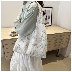 Detail of white chiffon tote bag featuring blue butterfly embroidery and fringe edges