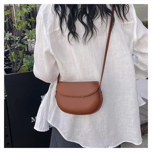 Detail of a brown PU leather saddle bag with smooth texture and adjustable strap