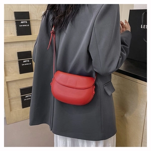 Red minimalist leather saddle bag shown in a stylish crossbody wear on a model