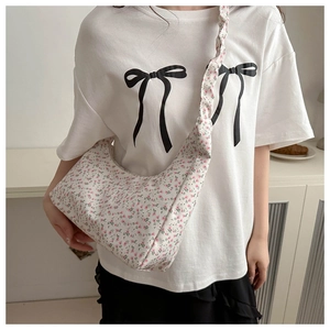 Gros plan du sac en toile à fleurs avec bandoulière froncée porté sur un t-shirt blanc