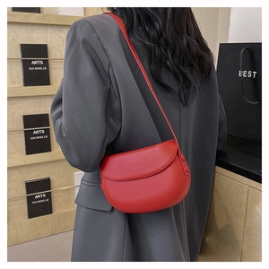 Close-up of bright red matte leather saddle bag with adjustable shoulder strap