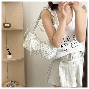 Detailed shot of floral armpit bag with ruffled shoulder strap and bow ribbon accents
