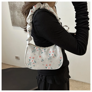 Detail of floral print tote bag with ruffled shoulder strap worn by a model