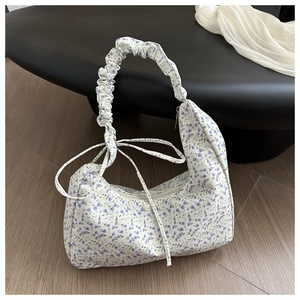 Detail view of floral oxford bag featuring a ruffled shoulder strap and side ribbon bow