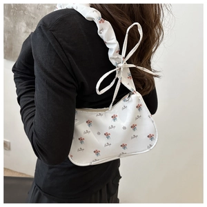 Detail of white floral armpit bag featuring a decorative ruffled bow shoulder strap