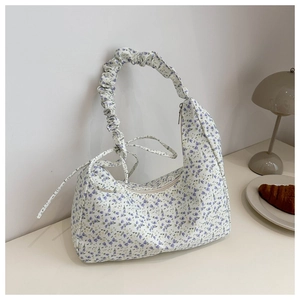 Detailed close-up of floral crescent bag with pleated handle and side ribbon knots
