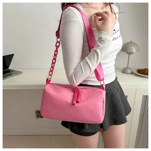 Détail du sac bandoulière en nylon rose avec grosse chaîne et cordon de fermeture tissé
