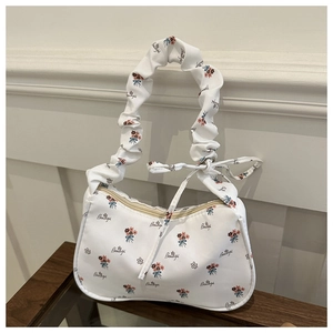 Detailed view of floral canvas handbag with ruffled strap and a decorative bow tie