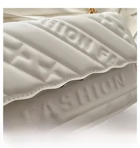 Detail view of white quilted faux leather bag with FASHION logo and star embossing